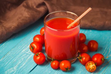 Mavi ahşap masa üzerinde gözlük domates suyu.