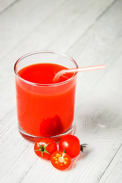 Beyaz ahşap masa üzerinde gözlük domates suyu. — Stok fotoğraf