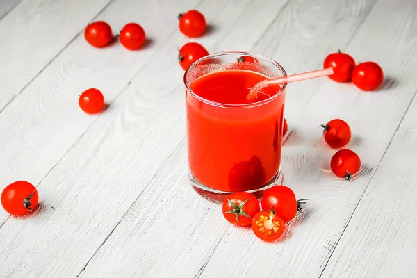 Beyaz ahşap masa üzerinde gözlük domates suyu. — Stok fotoğraf