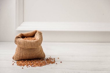 Beyaz arka plan üzerinde ham karabuğday ile küçük bir keten çuval. Geleneksel Rus mutfağı. Sağlıklı bir diyet kavramı.