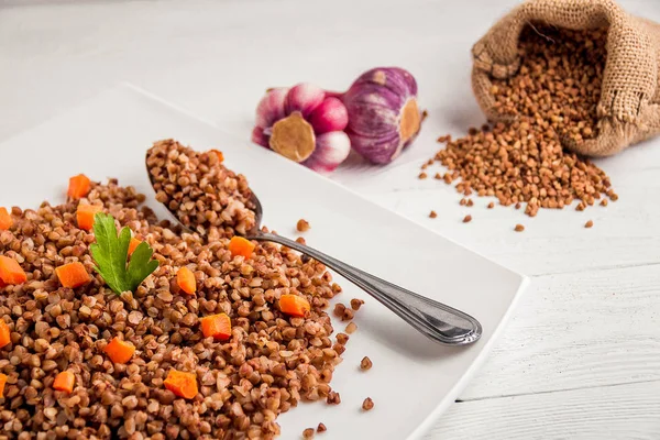 Beyaz ahşap masada beyaz tabak lezzetli karabuğday lapası..