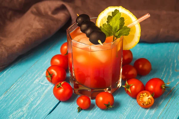 Cóctel Bloody Mary con hielo en vasos sobre mesa de madera azul . — Foto de Stock