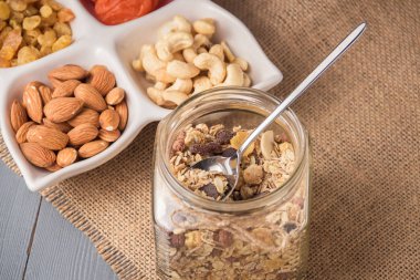 Kurutulmuş meyve ile Granola tahıl gevreği, gri ahşap masada kase fındık.