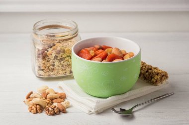 Kuru meyve ile granola tahıl gevreği, Beyaz ahşap masada yeşil kase fındık.