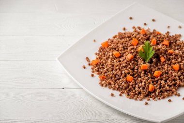 Beyaz ahşap masada beyaz tabak lezzetli karabuğday lapası..