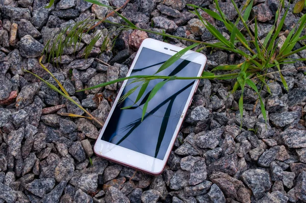 Smartphone with a broken screen. Broken phone on the stones.