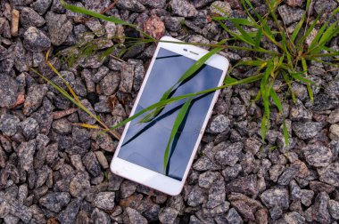 Ekranı kırık akıllı telefon. Kırık telefon taşların üzerinde..