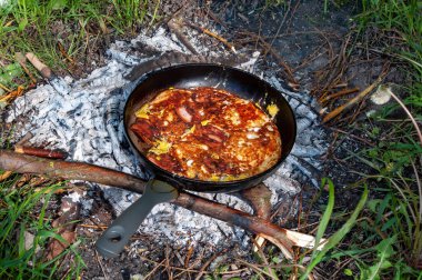 Kamp ateşinde yemek pişirmek, dökme demir tavada. bbq fotoğrafı