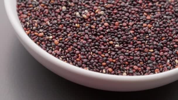 Graines de quinoa dans un bol blanc sur fond sombre rotation. Vue de dessus. Macro — Video