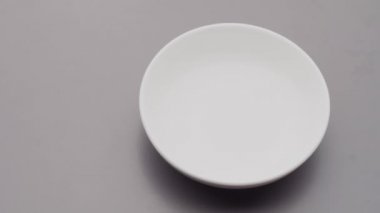 Kırmızı kinoa tohumları gri beton arka planda kaseye dökülüyor.