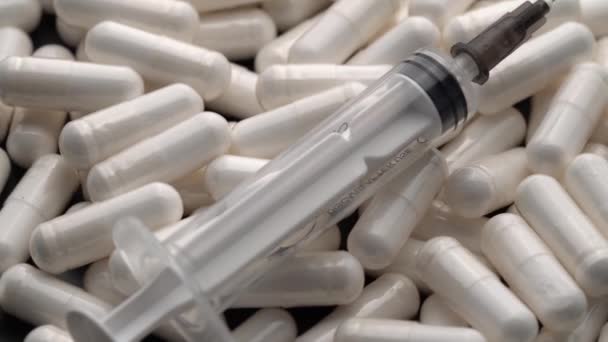 Comprimidos e cápsulas com uma seringa colocada por cima, girando em círculo — Vídeo de Stock