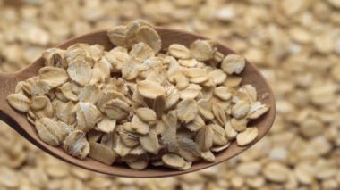 Kaşıkla yulaf ezmesi. Yulaf gevreği. Dönüşümlü yakın çekim. Kuru yulaf taneleri arka plan, dönüşümlü döngü döngüsü 4k üst görünümü kapatın. Yemek arkaplanı. Gastronomi konsepti, organik gıda. Makro dönüş yulafları.