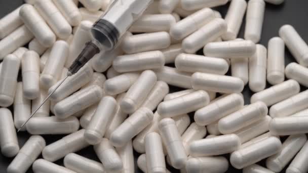 Pillen en capsules met een spuit bovenop, draaiend in een cirkel — Stockvideo