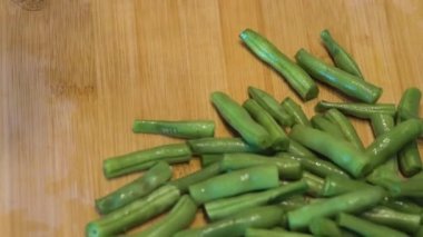 Kadın yeşil fasulyeleri kesiyor. Kapatın. Genç yeşil fasulyeleri budamak, ahşap kesme tahtasını kesmek.