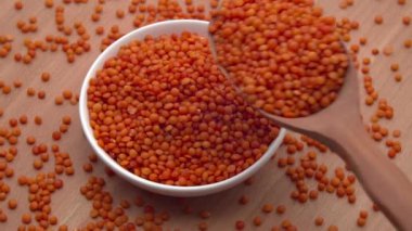 Kaşık, ahşap arka plandaki kaseye kırmızı mercimek döker. ProRes 422