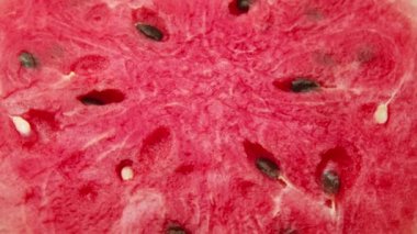 Kırmızı karpuz arka planda 4K ProRes 422 'de dönüyor. Ferahlatıcı ve sağlıklı sulu meyve. Yakın düz-yatay görünüm.