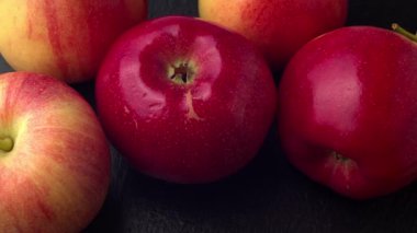 Lezzetli kırmızı elmalar hareket eden siyah taş tahtada yığılıyor. 4K ProRes 422