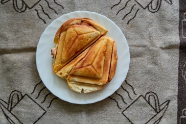 Sıcak Çıtır Sandviç. Kahvaltı için beyaz tabakta taze, çıtır çıtır, lezzetli tost makinesi. Kahvaltı için yemek. Vejetaryen yemeği..