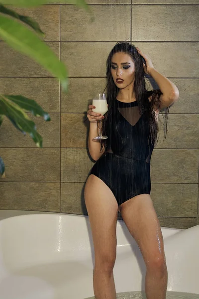 Kız banyoda bir bardak süt Holding'in bir siyah Mayo içinde. — Stok fotoğraf