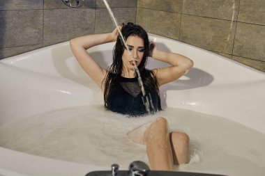 Süt banyosu içinde poz bir siyah Mayo içinde genç kadın.