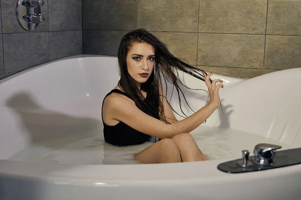 Junge Frau im schwarzen Badeanzug posiert im Milchbad. — Stockfoto