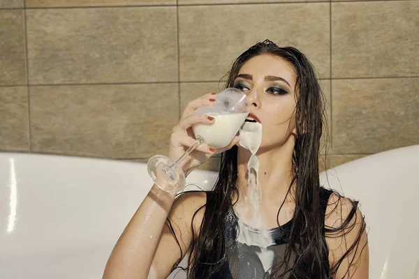 Jonge vrouw giet melk op zichzelf. Vrouw met vlekkerig make-up. — Stockfoto