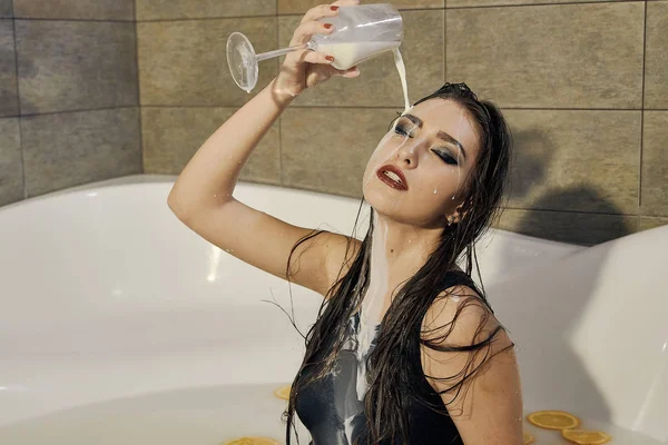 Ung kvinna häller mjölk på själv. Kvinna med utsmetade smink. — Stockfoto