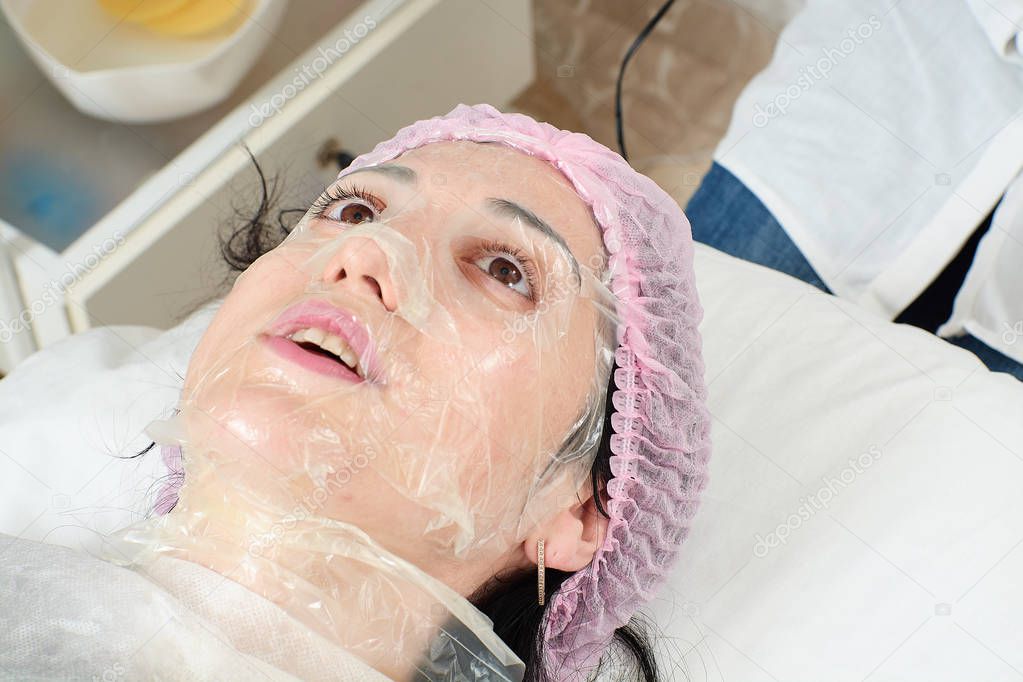 Young woman in beauty salon doing peeling and facial cleansing procedure.