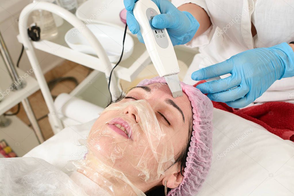 Young woman in beauty salon doing ultrasound peeling and facial cleansing procedure.