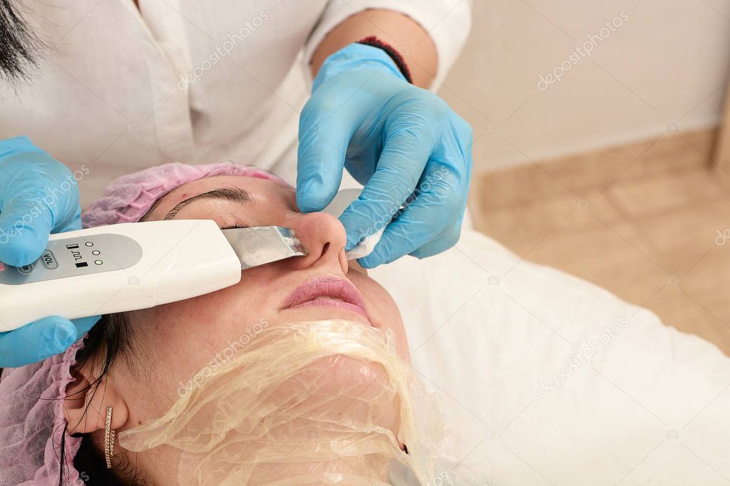 Young woman in beauty salon doing ultrasound peeling and facial cleansing procedure.