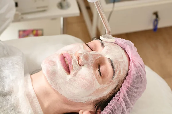Jonge vrouw in schoonheidssalon doet verjongende, toning procedure darsonval op het gezicht. — Stockfoto