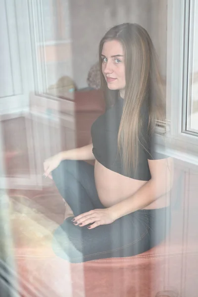 Молодая беременная женщина. Беременная красивая женщина позирует дома . — стоковое фото