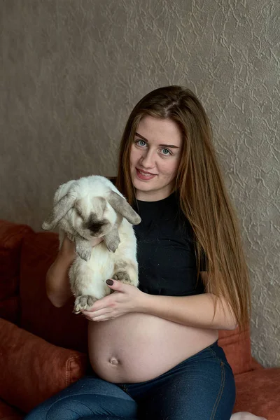 Fiatal terhes nő. Terhes, gyönyörű nő, nyúl pózol otthon. Boldog terhességet.. — Stock Fotó