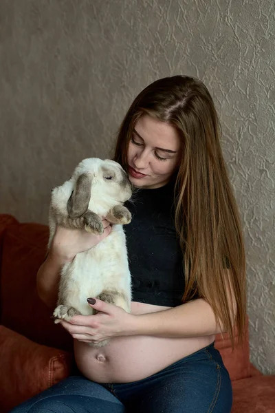 Jonge zwangere vrouw. Zwangere mooie vrouw met konijn die thuis poseert. Gelukkige zwangerschap. — Stockfoto