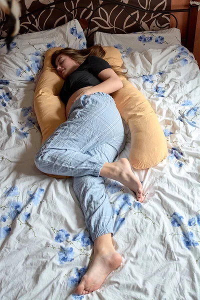 Young pregnant woman. Pregnant beautiful woman sleeps on maternity pillow in bed.