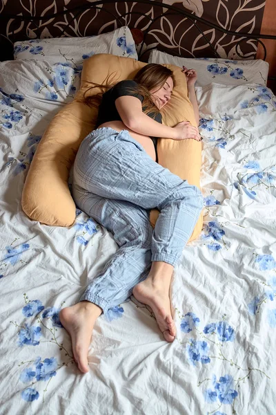 Młoda kobieta w ciąży. Ciężarna piękna kobieta śpi na poduszce ciążowej w łóżku. — Zdjęcie stockowe