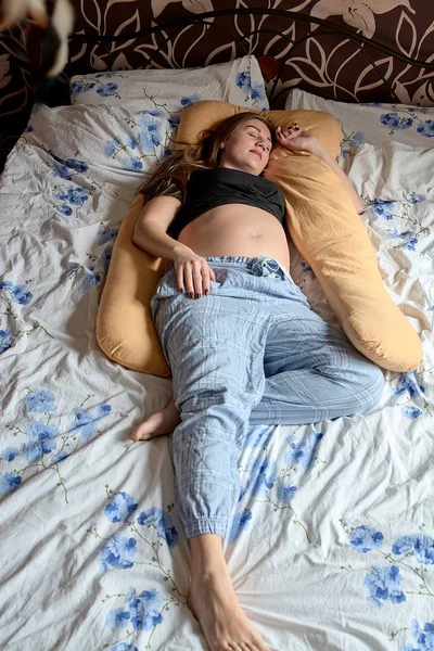 Mladá těhotná žena. Těhotná krásná žena spí na mateřském polštáři v posteli. — Stock fotografie