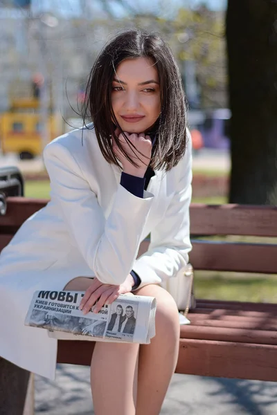 Elinde bir gazete ile bir şehir sokakta zarif genç kadın.