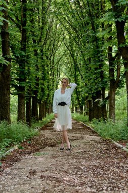 Sarışın kadın şehir parkında kestane sokak boyunca tek başına yürüyor. Genç kadın modern portre.