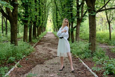 Sarışın kadın şehir parkında kestane sokak boyunca tek başına yürüyor. Genç kadın modern portre.