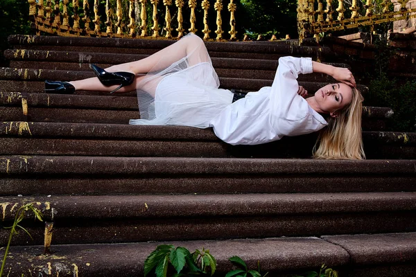 Mujer rubia se sienta en los escalones de la vieja escalera de granito. Mujer joven retrato moderno . — Foto de Stock