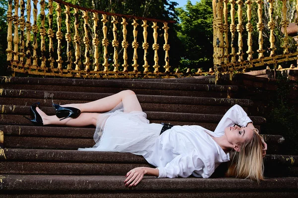Mujer rubia se sienta en los escalones de la vieja escalera de granito. Mujer joven retrato moderno . — Foto de Stock