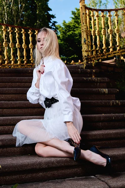 Sarışın kadın eski granit merdivenmerdivenlerinde oturur. Genç kadın modern portre.