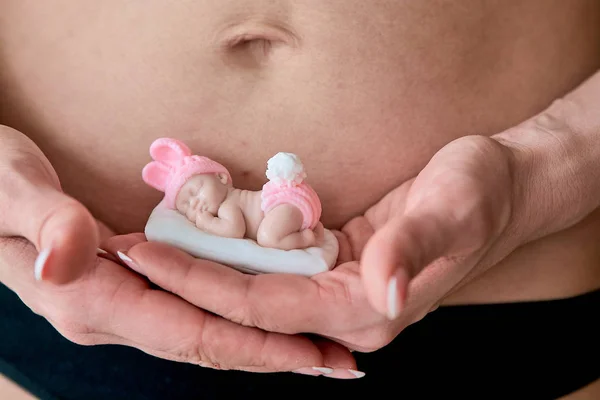 怀孕的年轻保姆拿着一个新生女婴形状的肥皂雕像. — 图库照片