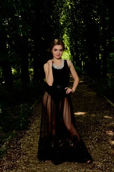 Young attractive woman is wearing the sexy transparent black dress. Young woman modern portrait.