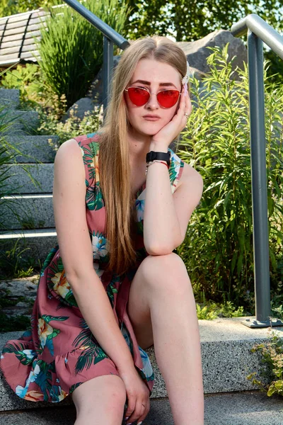 Νέα ελκυστική γυναίκα. Κόκκινα γυαλιά ηλίου, έγχρωμο φόρεμα. Πορτραίτο κοριτσιού. — Φωτογραφία Αρχείου