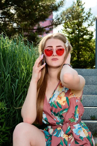 Jovem mulher atraente. Óculos de sol vermelhos, vestido de cor, telefone celular, 5G, 4G, 3G, 2G, rede LTE . — Fotografia de Stock