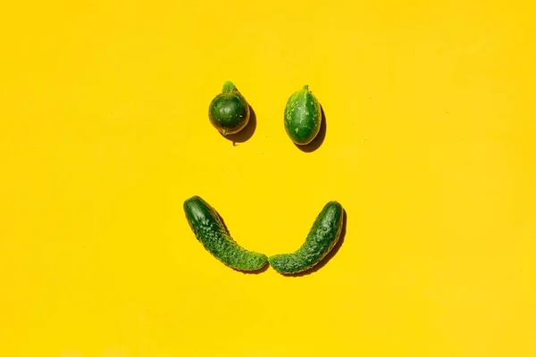 Different sizes and forms cucumbers on a yellow background forms a smiling face.