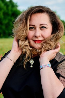 Artı yeşil buğday ve yabani haşhaş bir alanda siyah elbiseli bir kadın. Kilolu şişman kadın.