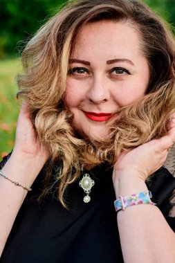 Artı yeşil buğday ve yabani haşhaş bir alanda siyah elbiseli bir kadın. Kilolu şişman kadın.